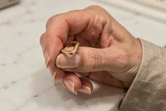 Main de femme tenant une vieille bague en or déformée au-dessus d'un comptoir en marbre dans une bijouterie