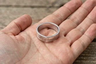 Bague coeur magnétique en argent avec gravure romantique posée dans une paume ouverte, vue macro en gros plan