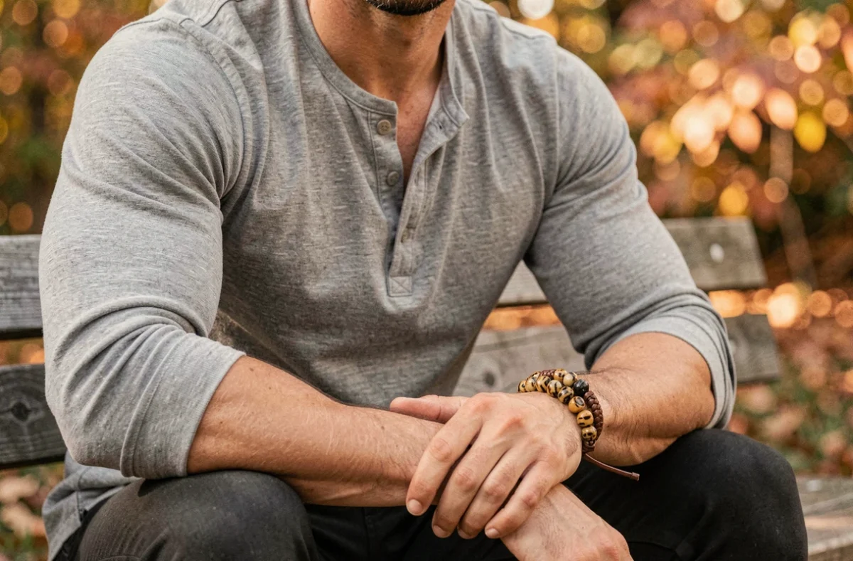 Homme sportif avec bracelet œil du tigre et bracelet cuir empilés sur fond de feuillage automnal