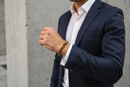 Homme élégant portant un bracelet œil du tigre en perles dorées sur fond urbain béton