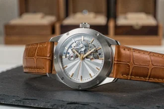 Montre mécanique de luxe en platine avec tourbillon visible sur ardoise noire dans un atelier horloger